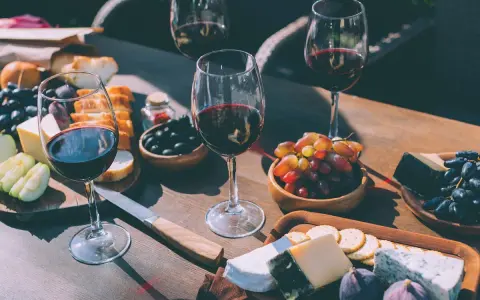 Degustacja merlot: jakie to wino? Kieliszki czerwonego wina, sery, winogrona, oliwki i pieczywo tworzą idealną kompozycję.