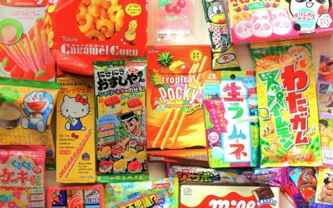 Un surtido vibrante de chuches famosas japonesas, incluyendo Pocky, Caramel Corn y dulces de Hello Kitty y Doraemon.