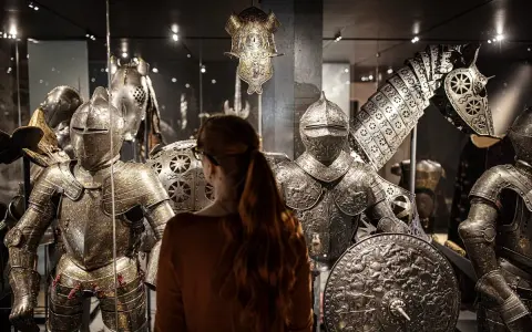 En kvinna betraktar rustningar och en hästrustning på Livrustkammaren Stockholm.