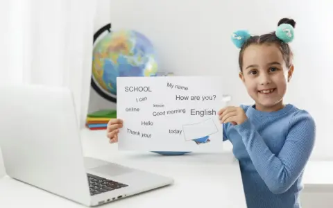 Uśmiechnięta 7 latek pokazuje kartkę z angielskimi słówkami: "English", "Hello", "Thank you!".