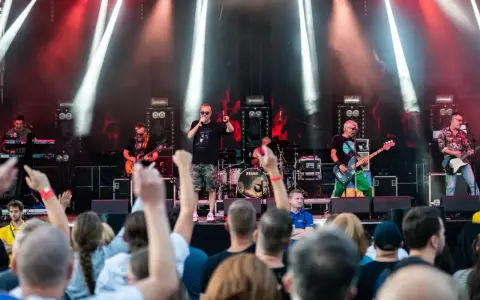 Zespół gra na scenie podczas festiwalu w Jarocinie. Widać publiczność, światła i instrumenty.