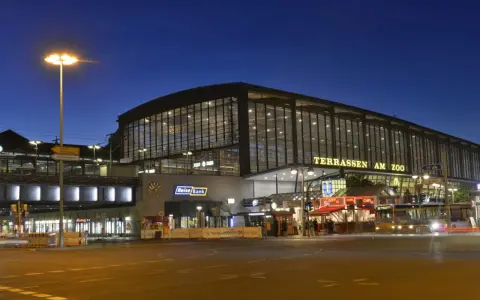 Der Bahnhof Zoo in Berlin bei Nacht. Die beleuchteten Terrassen am Zoo erstrahlen im Dunkeln.