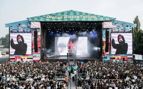 Tłum ludzi na Orange Warsaw Festival 2026, scena z artystą na ekranie i dymem.