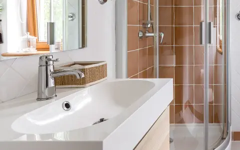 Bagno moderno con lavabo bianco, rubinetteria cromata e doccia con piastrelle color terra. Ideale per misure minime mini bagni piccoli progetti.