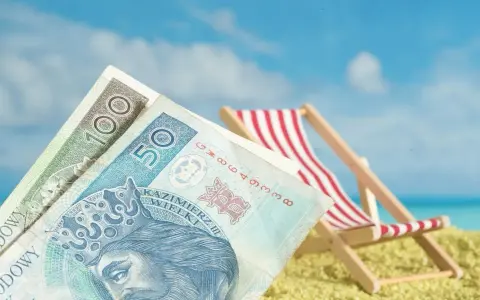 Pieniądze na plaży, leżak i błękitne niebo. Czy to symboliczne przedstawienie opłaty klimatycznej za wakacyjny wypoczynek?