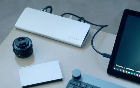 Stacja dokująca ICY BOX podłączona do laptopa, obok obiektyw Sony i dysk Porsche Design.
