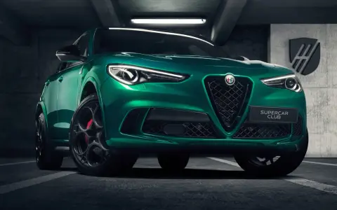 Zielony Alfa Romeo Stelvio Quadrifoglio z czarnymi felgami i czerwonymi zaciskami hamulcowymi, zaparkowany w garażu.