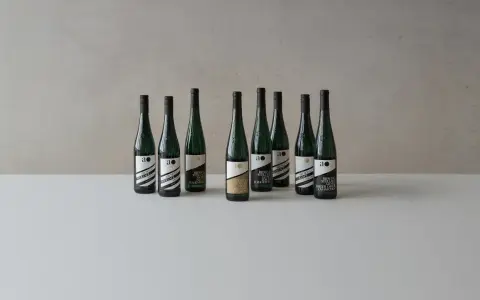Neun Flaschen Wein der Andreas Oster Weinkellerei stehen nebeneinander.