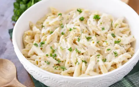 Penne w kremowym sosie śmietanowym, posypane świeżą natką pietruszki. Idealne na szybki obiad.
