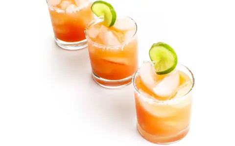 Drei erfrischende Salty Dog Cocktails mit Eis und Limettenspalten, bereit zum Genießen.