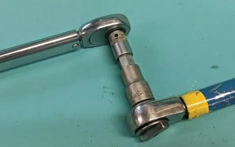 Två verktyg kopplade för att kalibrera momentnyckel. En momentnyckel i metall och en blå/gul skruvdragare med hylsa.