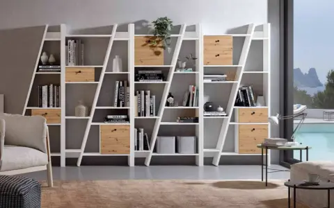 Estanterías blancas con cajones de madera, llenas de libros y objetos decorativos. La decoración de estanterías es clave para un hogar moderno.