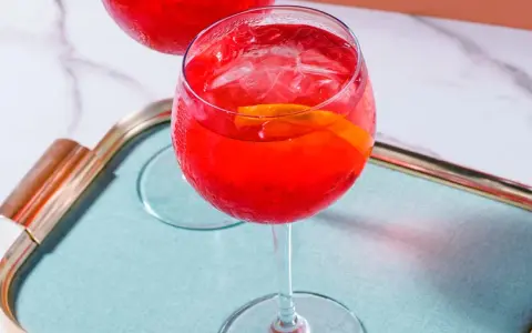 Ein erfrischender Campari Spritz mit Eis und Orangenscheibe auf einem Tablett.