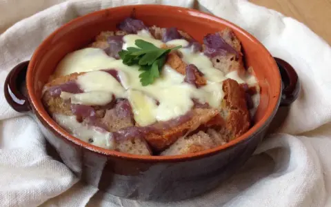 Zuppa di cipolle toscana fumante, con crostini dorati e formaggio filante, guarnita con prezzemolo fresco.