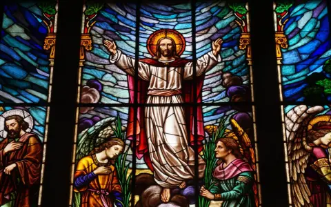 Magnifique vitrail d'église représentant le Christ entouré d'anges et de saints, baigné de lumière.