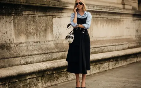 Mujer con un elegante vestido negro sobre una camisa blanca, hablando por teléfono.