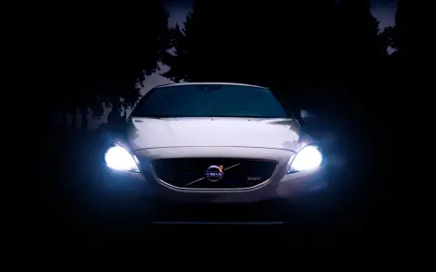 Volvo blanco con luces encendidas en la oscuridad.