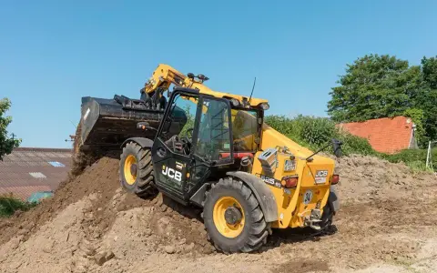 Żółty ładowarka teleskopowa JCB 525-60 z podniesionym wysięgnikiem i łyżką, pracująca na budowie.
