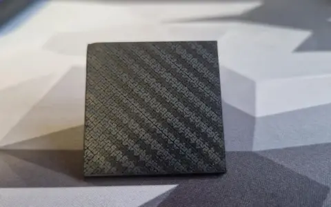 A small cube with a textured surface, showcasing the intricate pattern achieved through carbon fiber 3D printing.