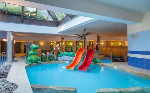 Karpacz hotel z basenem i atrakcjami dla dzieci: zjeżdżalnie, basen, zielone dinozaury i tropikalne dekoracje.