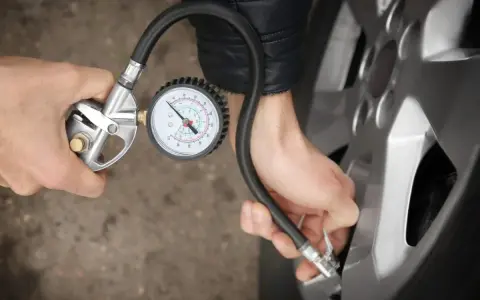 Person prüft den Reifendruck mit einem Manometer. Die warmen Reifen sind wichtig für die Sicherheit.