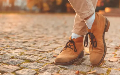 Herbstliche Stiefeletten aus Nubukleder, was das ist, zeigen sich auf einem Kopfsteinpflaster.