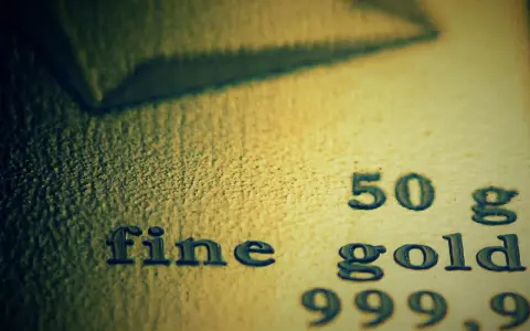 Zbliżenie na tekst "fine gold 50 g 999,9" wybity na powierzchni złota.
