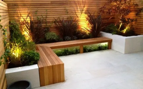 Elegante decoracion patio interior con banco de madera y plantas iluminadas.