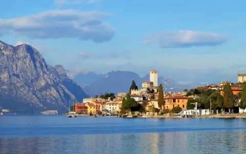 Borgo sul lago di Garda con castello e montagne sullo sfondo. Un luogo incantevole da esplorare, scopri cosa vedere!
