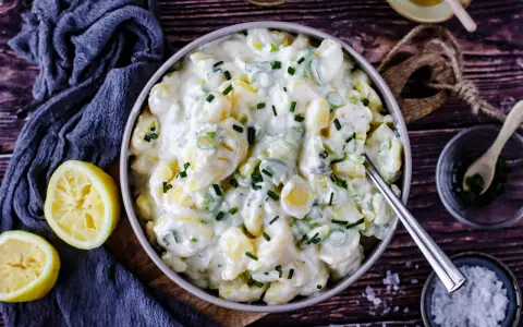 Cremiger Kartoffelsalat mit Joghurt, garniert mit Schnittlauch. Dazu passen frische Zitronenspalten.