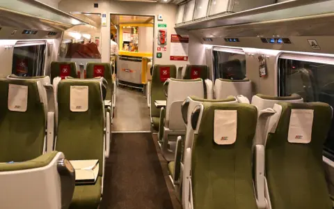 Wnętrze wagonu PKP Intercity IC 4520 Hutnik. Rozkład miejsc w zielonych fotelach, z widocznym barem Wars.