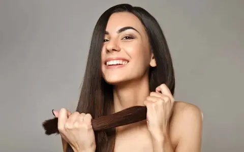 Mujer sonriente muestra su cabello largo y sedoso, un ejemplo de cómo cuidar el pelo para que luzca saludable y brillante.