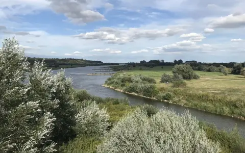 Malowniczy krajobraz z rzeką i zielonymi wzgórzami, idealny na sandomierz trasy rowerowe.