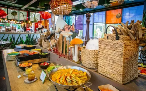 Buffet coloré avec des plats de courges, salades et fruits. Décoration ludique avec des champignons et un personnage de conte de fées, dans l'ambiance du resto Futuroscope.