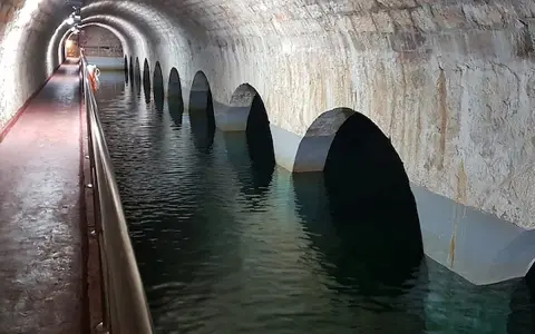 Interior de aljibes de agua abovedados, con arcos que se sumergen en el agua. Un pasillo con barandilla recorre el lateral.