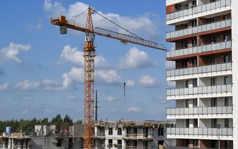 Plac budowy, gdzie lex deweloper wznosi nowoczesne apartamenty. Widoczny dźwig budowlany i postępujące prace.