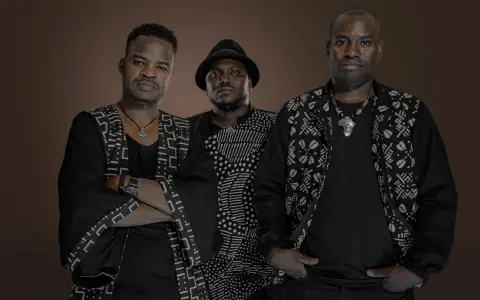Trois hommes en tenue traditionnelle africaine, évoquant l'ancêtre du blues, posent avec assurance.