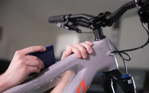 Hands apply protective film to a mountain bike frame. This bike is ready for any terrain, whether trails or roads.