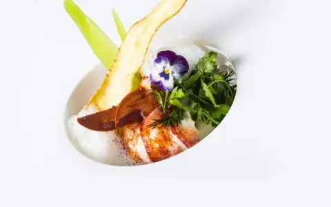 Homard poêlé, écume légère, chips de légume et fleur, une spécialité jurassienne raffinée.