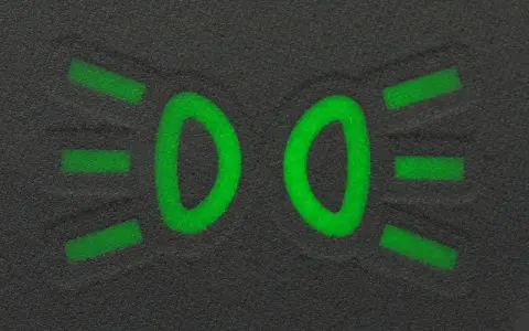 Zielony symbol świateł mijania na ciemnym tle.