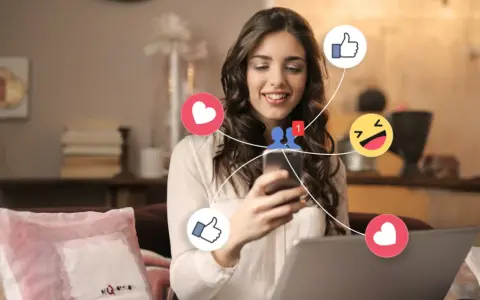 Ung kvinna ler när hon använder sin telefon, omgiven av sociala medieikoner som hjärtan och tummen upp. Hon upplever positiva saker med sociala medier.