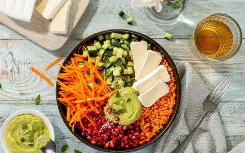 Bunter rote Linsen Salat mit Gurke, Karottenstreifen, Granatapfelkernen, Avocado-Dip und Brie-Käse.