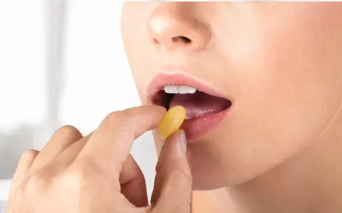 Donna inserisce una capsula gialla in bocca. Per l'assunzione di Ciproxin, stomaco pieno o vuoto, consultare il medico.