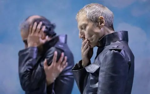Kjell Brutscheidt, con le mani sul volto, esprime angoscia. L'altro uomo, sfocato, si copre le orecchie.