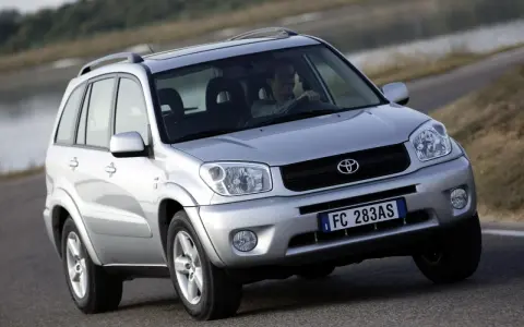 Srebrny SUV Toyota RAV4 na drodze, z kierowcą za kierownicą.