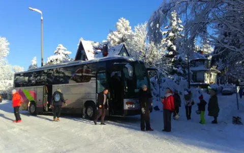 Grupa turystów wysiada z autobusu w zimowej scenerii. To **białka tatrzańska termy trasa** – idealne miejsce na zimowy wypoczynek.