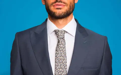 Uomo con abito blu, camicia bianca e cravatta fantasia. Un abbinamento classico per un look elegante.