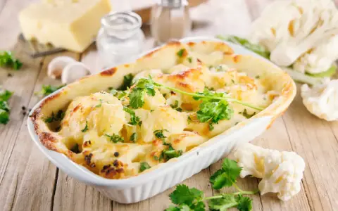 Un délicieux gratin de chou-fleur doré et gratiné, garni de persil frais, prêt à être dégusté.
