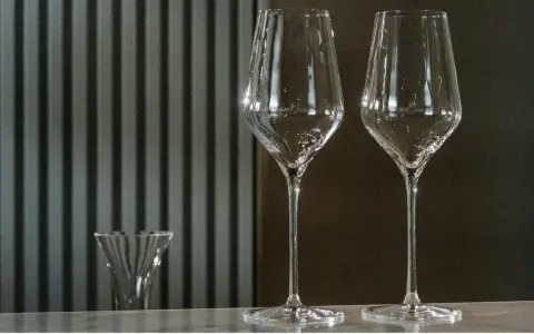 Dwa wysokie kieliszki do wina stoją obok siebie. Z lewej strony widać mniejszy kieliszek. Zastanawiasz się, jakie kieliszki do jakiego wina?