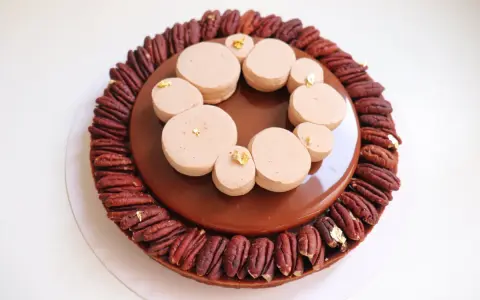 Tarte chocolat noix de pécan, un délice gourmand avec une ganache brillante et des touches de feuille d'or.